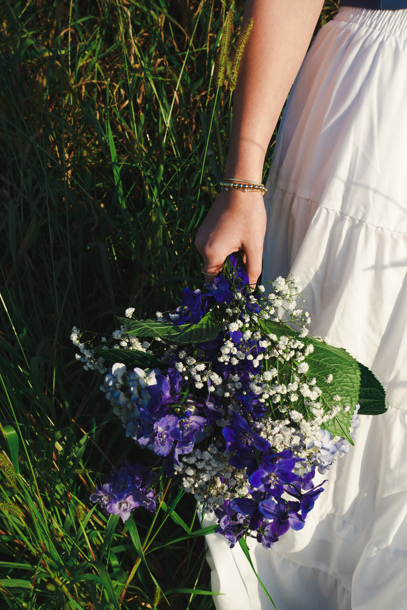 Close detail of purple and white bouquet held beside a white skirt during a senior portrait session in Northwest Indiana.