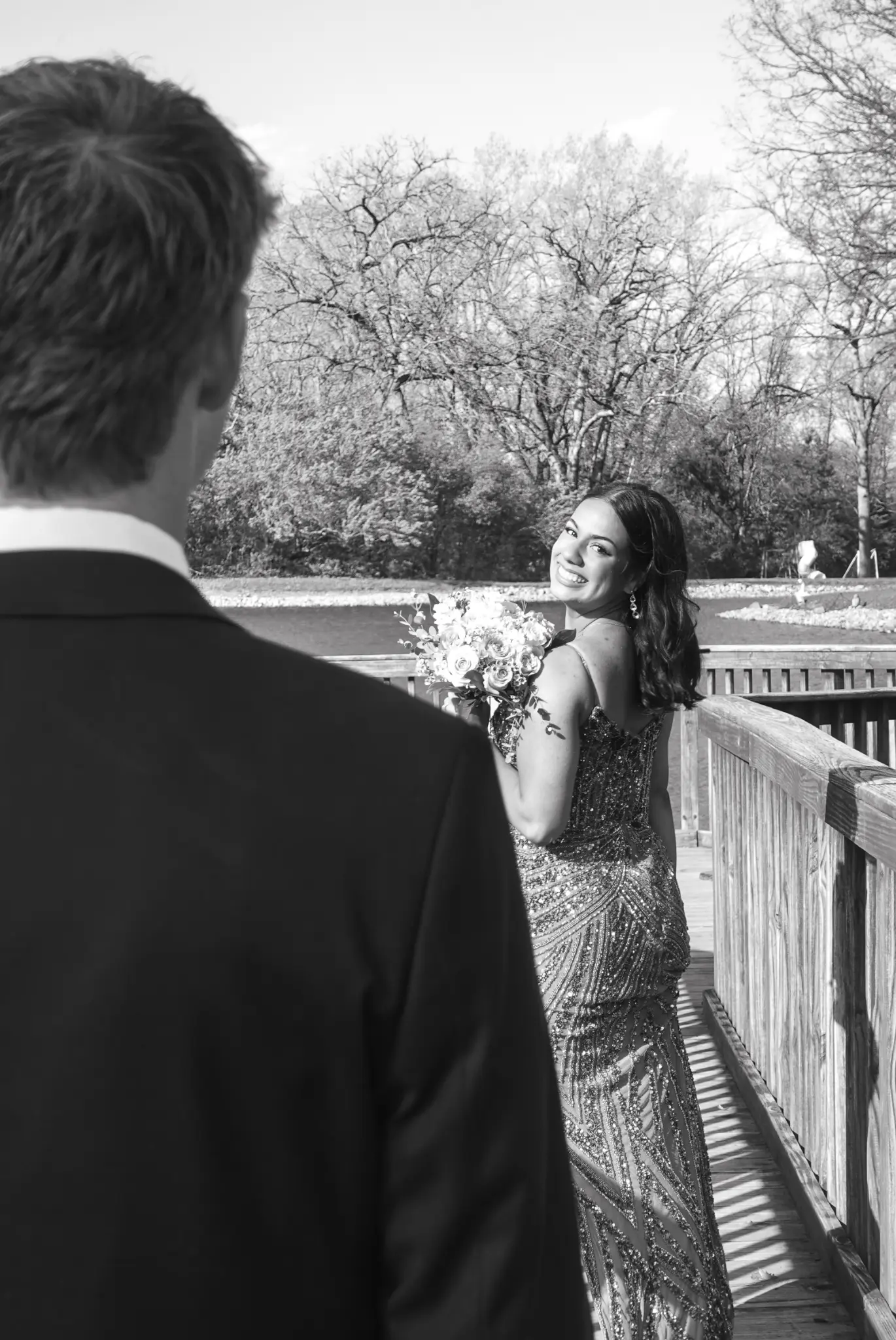 Black and white prom photo of a smiling client holding flowers on a bridge in Northwest Indiana.