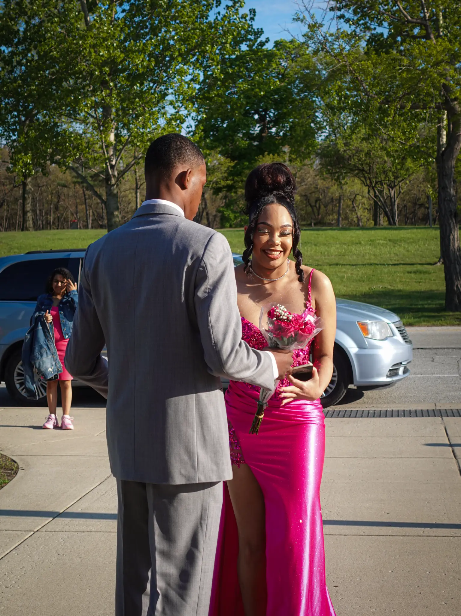 Prom couple exchanging flowers during an outdoor arrival moment in bright sunlight in Northwest Indiana.