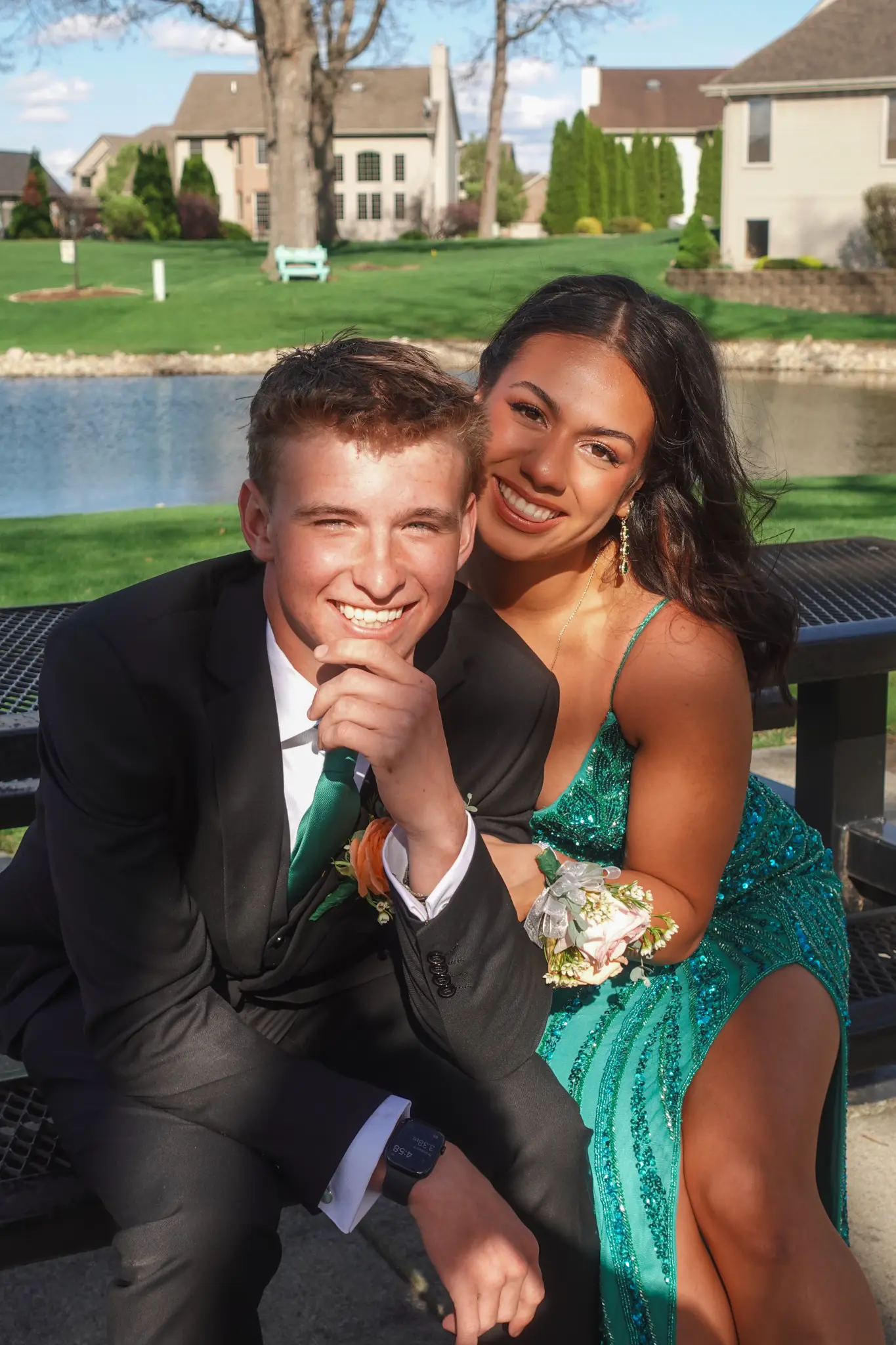 Prom couple smiling together while seated near a lake in formal attire in Northwest Indiana.