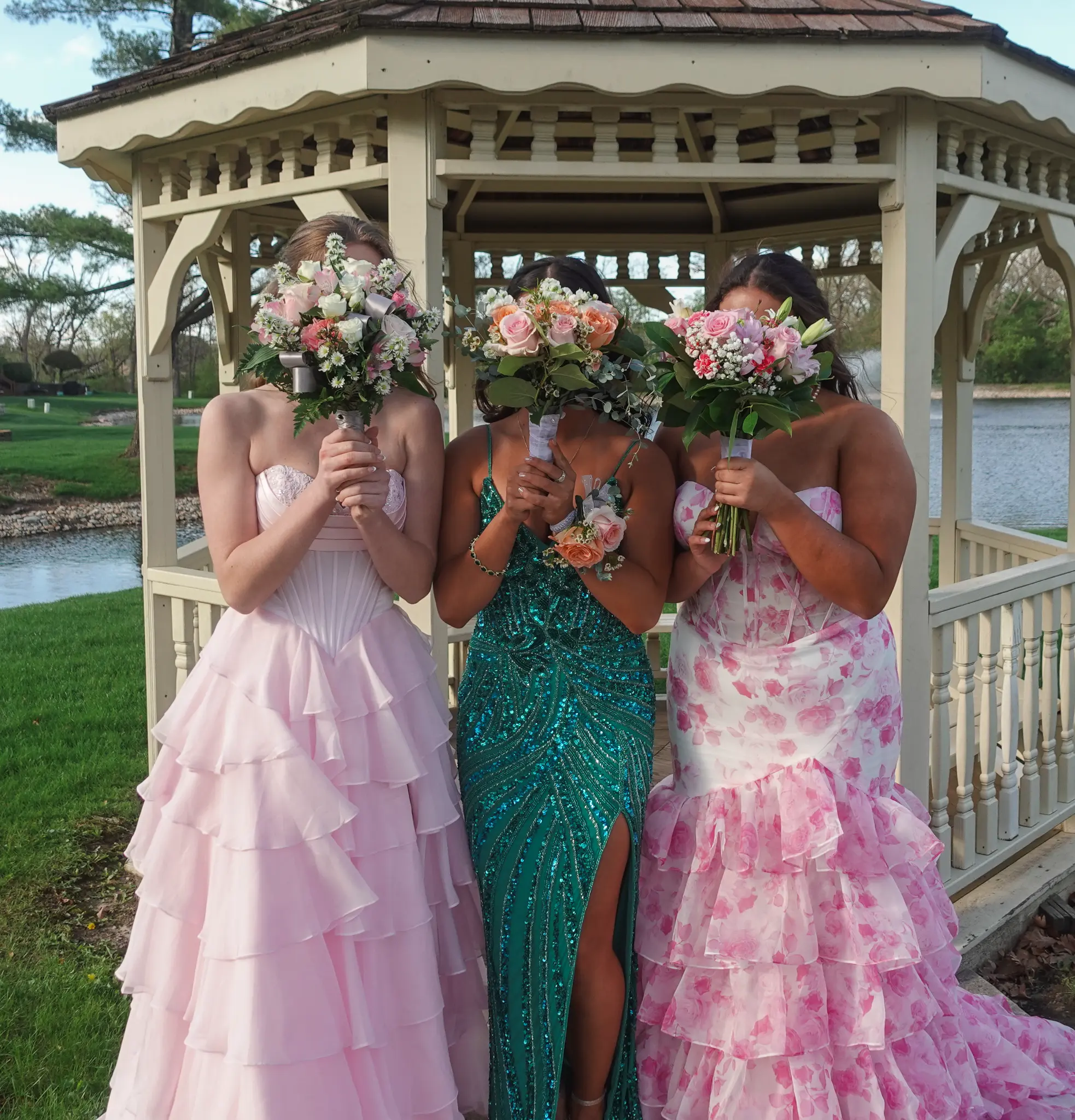 Three prom clients holding bouquets in front of their faces while standing in a gazebo in Northwest Indiana.